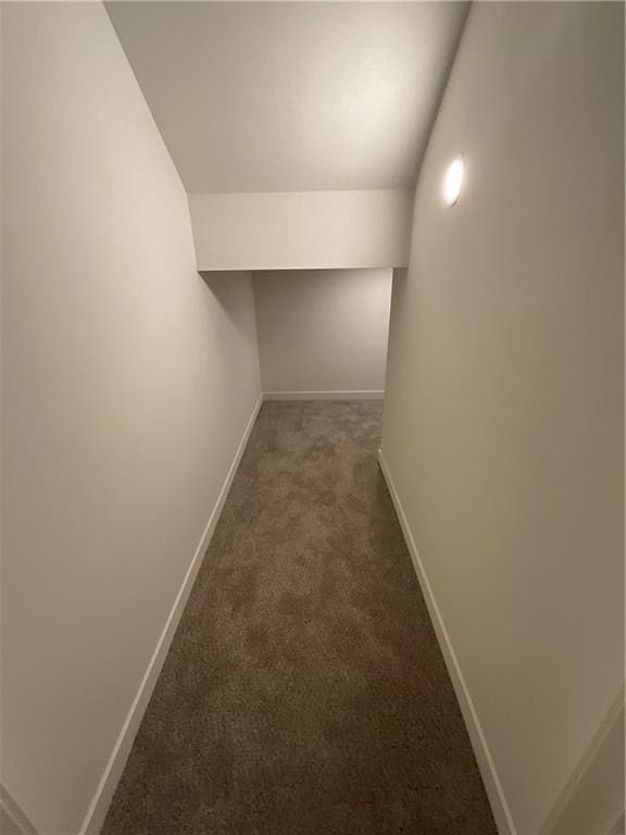 corridor with lofted ceiling, baseboards, and carpet flooring