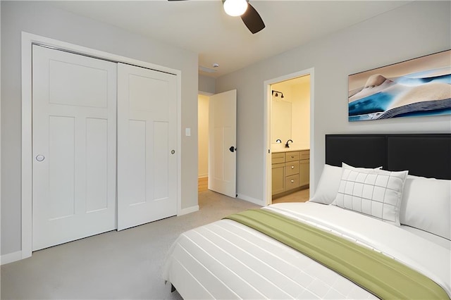 bedroom featuring a closet, a ceiling fan, light carpet, connected bathroom, and baseboards