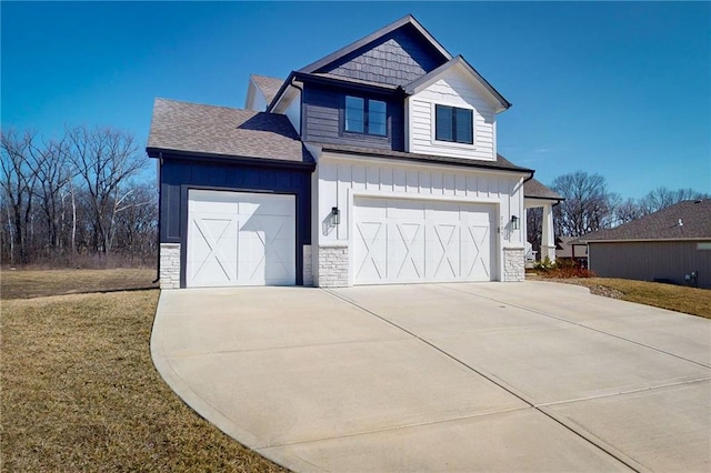 view of front facade featuring board and batten siding, a front yard, a garage, stone siding, and driveway