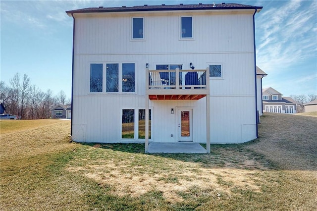 rear view of property featuring a balcony, a yard, and a patio area