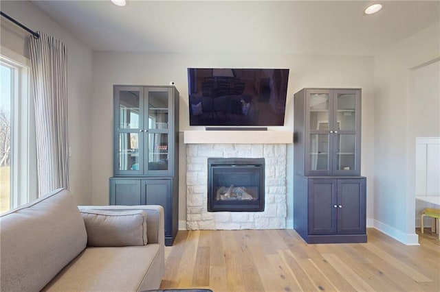 unfurnished living room featuring recessed lighting, a fireplace, baseboards, and wood finished floors