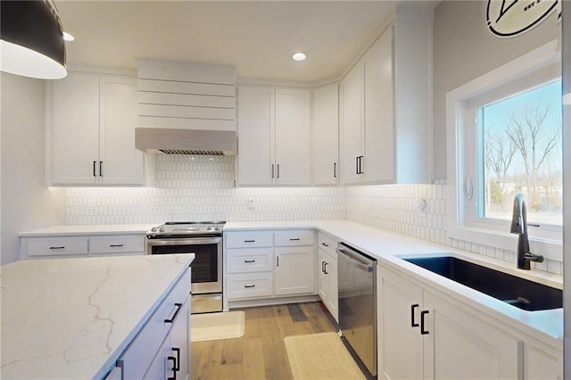 kitchen with a sink, light wood-style floors, appliances with stainless steel finishes, and white cabinets