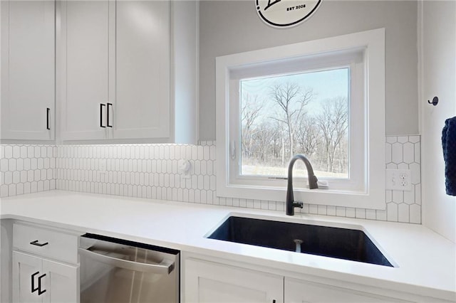 kitchen featuring dishwasher, white cabinets, and a sink