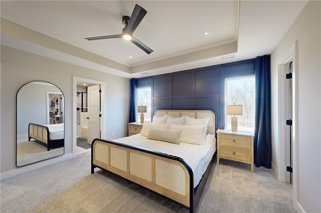 bedroom with crown molding, baseboards, ceiling fan, light colored carpet, and a raised ceiling