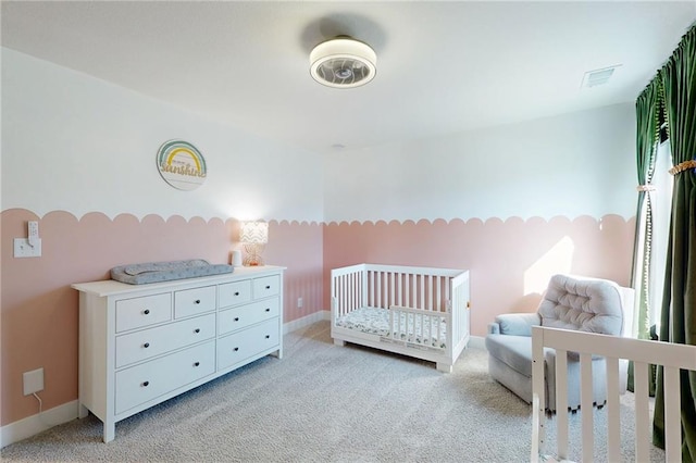 bedroom featuring light carpet, visible vents, a nursery area, and baseboards