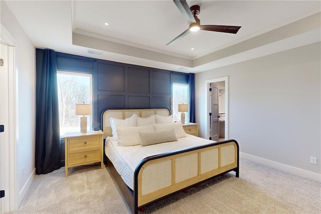 bedroom with a tray ceiling, light colored carpet, ornamental molding, and a decorative wall