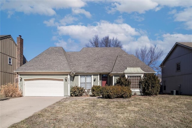 view of front of house with a front yard, an attached garage, driveway, and roof with shingles