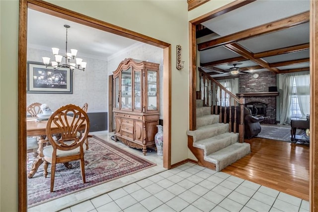 dining space with coffered ceiling, stairway, light tile patterned flooring, a brick fireplace, and a chandelier