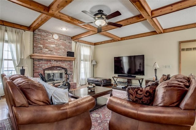 living area with beamed ceiling, a ceiling fan, coffered ceiling, wood finished floors, and a brick fireplace