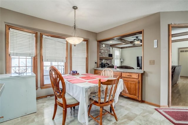 dining space with beam ceiling, baseboards, and a ceiling fan