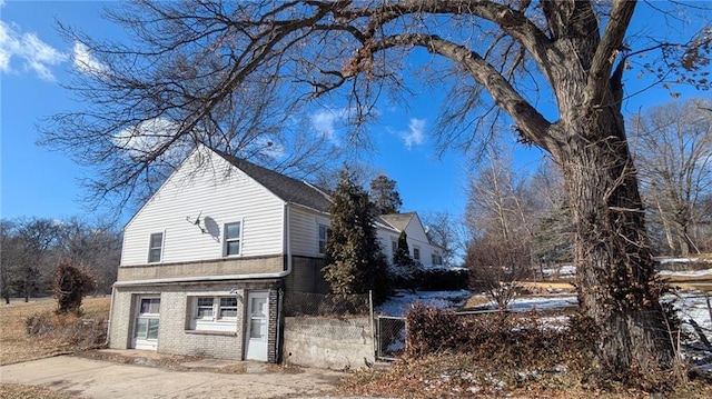 view of side of home with brick siding and fence