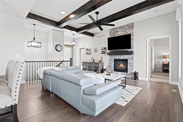 living area with ceiling fan with notable chandelier, visible vents, baseboards, beamed ceiling, and dark wood finished floors