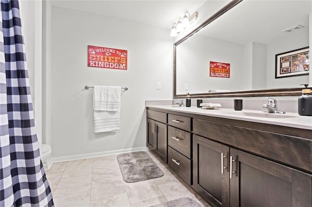 full bathroom featuring double vanity, baseboards, visible vents, toilet, and a sink