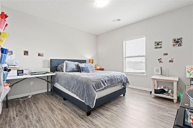 bedroom featuring visible vents, baseboards, and wood finished floors