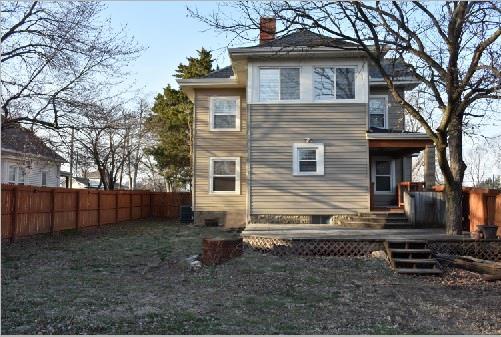 rear view of house with a chimney and fence