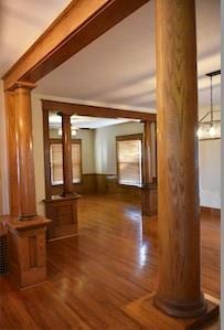 corridor featuring beam ceiling, decorative columns, and wood finished floors