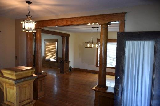 unfurnished dining area with an inviting chandelier, a healthy amount of sunlight, baseboards, and dark wood-type flooring