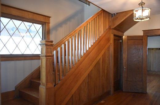 stairs featuring an inviting chandelier and wood finished floors