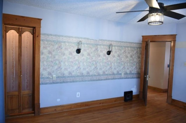 spare room with baseboards, a textured ceiling, a ceiling fan, and wood finished floors