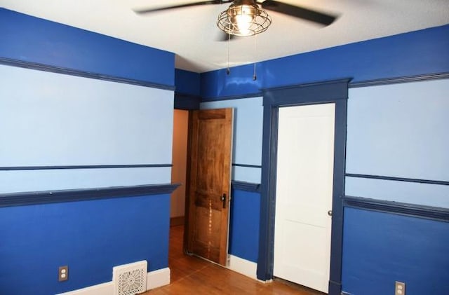 unfurnished bedroom featuring wood finished floors, baseboards, visible vents, and ceiling fan