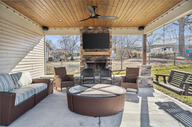 view of patio / terrace with an outdoor living space with a fireplace, a ceiling fan, and fence