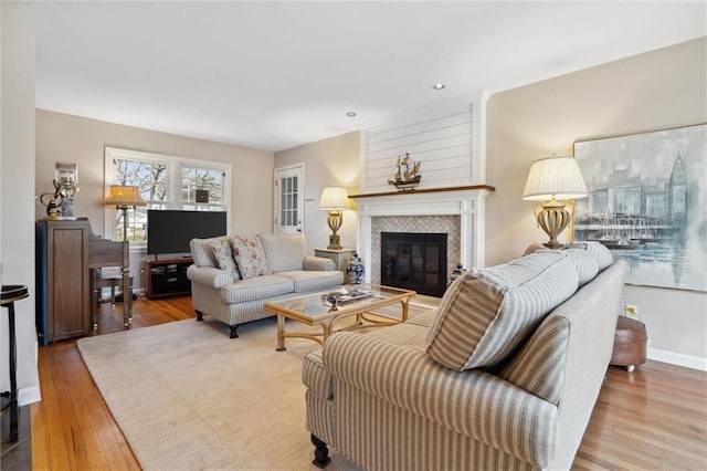 living room with recessed lighting, baseboards, wood finished floors, and a tile fireplace