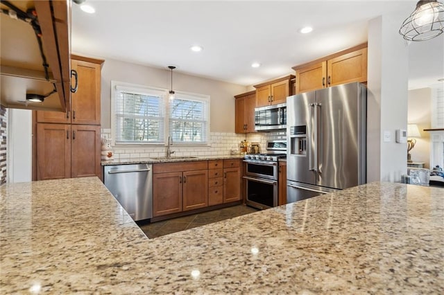 kitchen featuring tasteful backsplash, brown cabinets, appliances with stainless steel finishes, and a sink