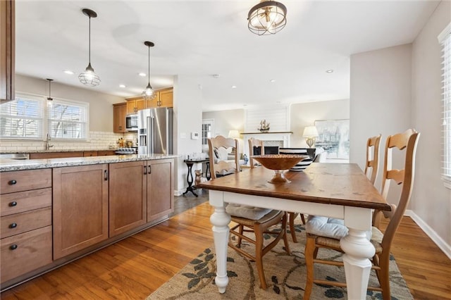 dining area featuring recessed lighting, a fireplace, baseboards, and wood finished floors