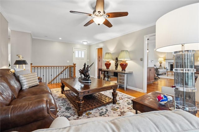 living area featuring a fireplace with raised hearth, crown molding, baseboards, and wood finished floors