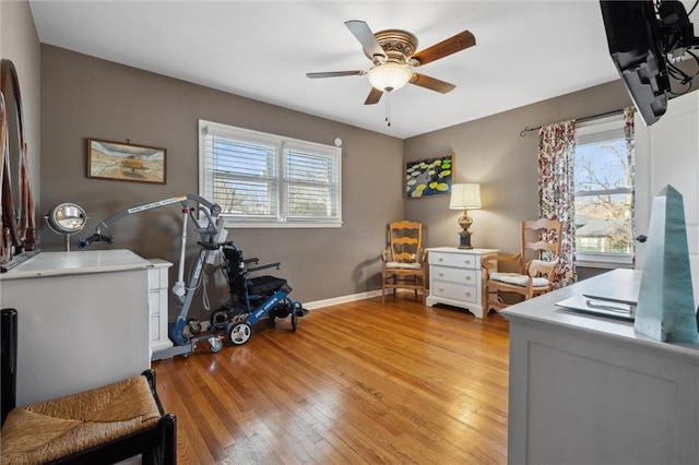 office space featuring baseboards, ceiling fan, and light wood finished floors