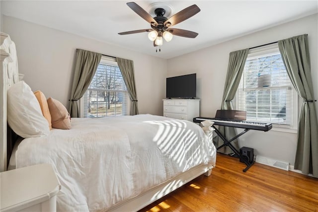 bedroom with wood finished floors, visible vents, and ceiling fan