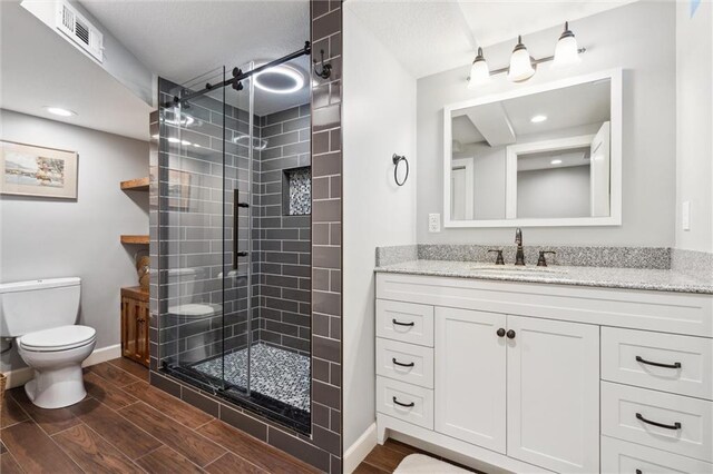 bathroom with visible vents, a shower stall, toilet, and wood finish floors