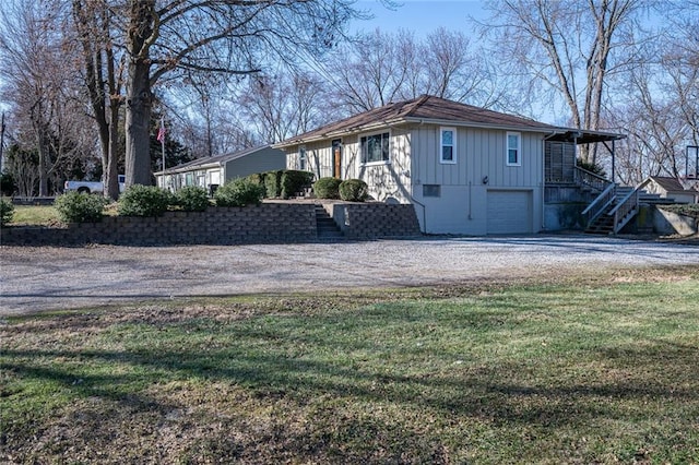 view of front of home with driveway, stairway, board and batten siding, a front yard, and an attached garage