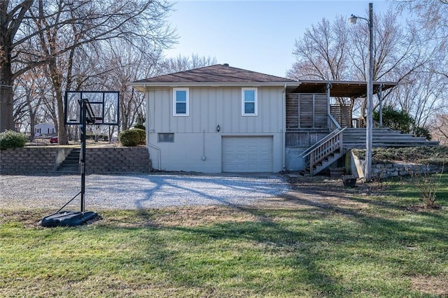 exterior space with a garage, a lawn, gravel driveway, and stairs