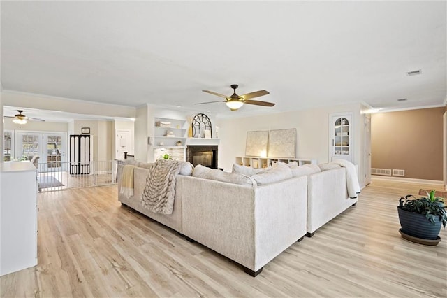 living room with light wood finished floors, ceiling fan, and ornamental molding