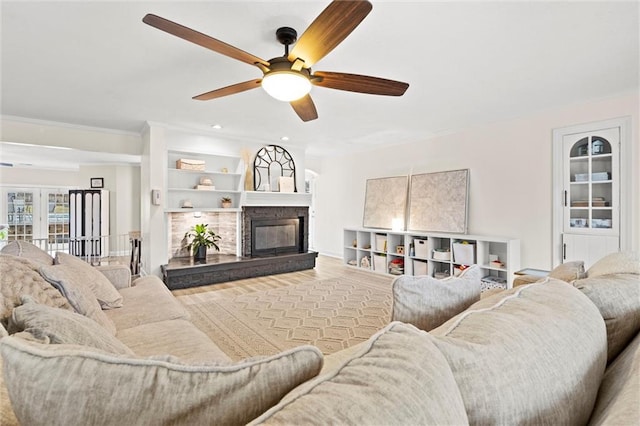 living room with a glass covered fireplace, wood finished floors, recessed lighting, crown molding, and ceiling fan