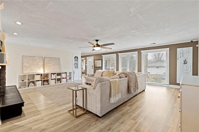 living room featuring light wood-style flooring, a ceiling fan, and a textured ceiling