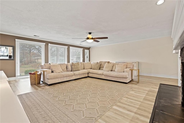 living area featuring crown molding, baseboards, light wood-type flooring, and ceiling fan