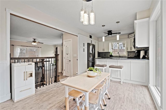 dining room featuring light wood-style flooring and ceiling fan with notable chandelier