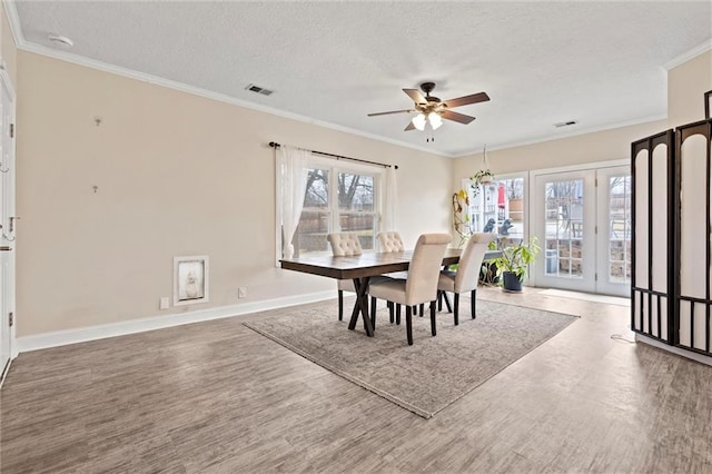 dining space with visible vents, ceiling fan, ornamental molding, wood finished floors, and a textured ceiling