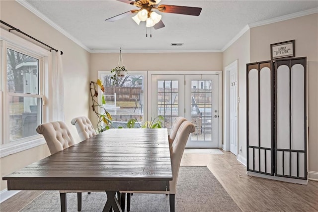 dining room with a textured ceiling, wood finished floors, a ceiling fan, and crown molding