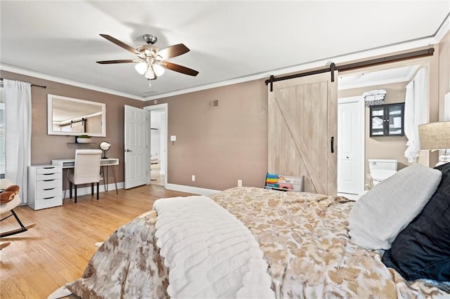 bedroom featuring a barn door, wood finished floors, crown molding, and baseboards