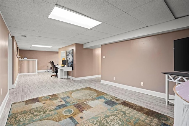 interior space with a drop ceiling, baseboards, and wood finished floors