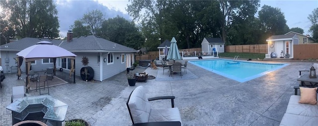 view of pool featuring a patio, an outbuilding, a fenced in pool, fence, and a storage unit