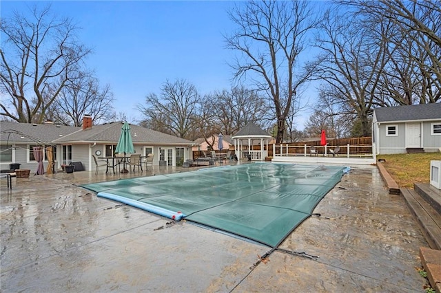 community pool with a gazebo, an outdoor structure, a patio, and fence