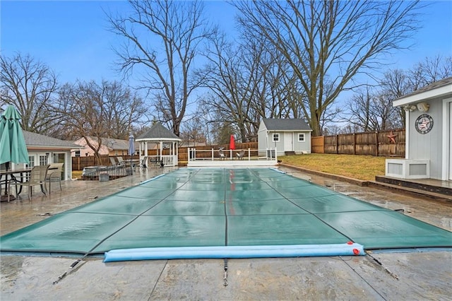 view of swimming pool featuring a patio, a yard, a fenced backyard, a gazebo, and an outdoor structure