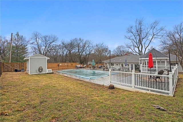 view of yard featuring a fenced in pool, a fenced backyard, an outdoor structure, a storage unit, and a patio