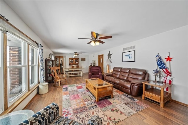 living area with ceiling fan, visible vents, baseboards, and wood finished floors