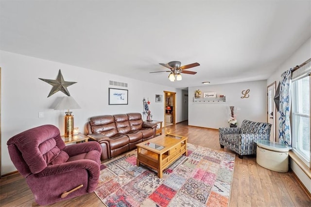 living room with a ceiling fan, wood finished floors, and visible vents