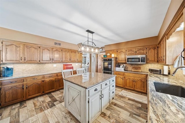 kitchen featuring a sink, stainless steel appliances, light wood-style floors, decorative backsplash, and light stone countertops